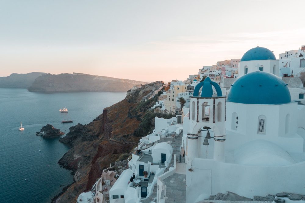 white buildings with blue domed roofs overlooking body of water in Greece