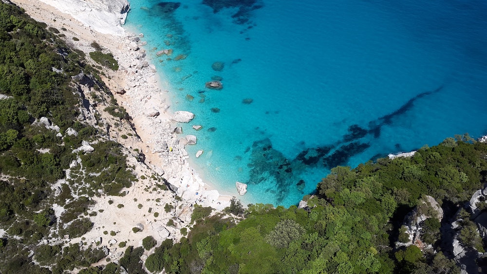 aerial view of rocky cliffs next to crystal clear waters