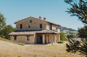 rustic Italian stone villa located on a green hill with bright blue skies