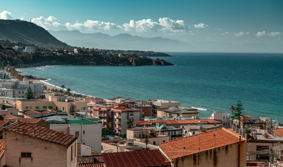Terracotta houses line the coast of one of the best Italian Islands for families.