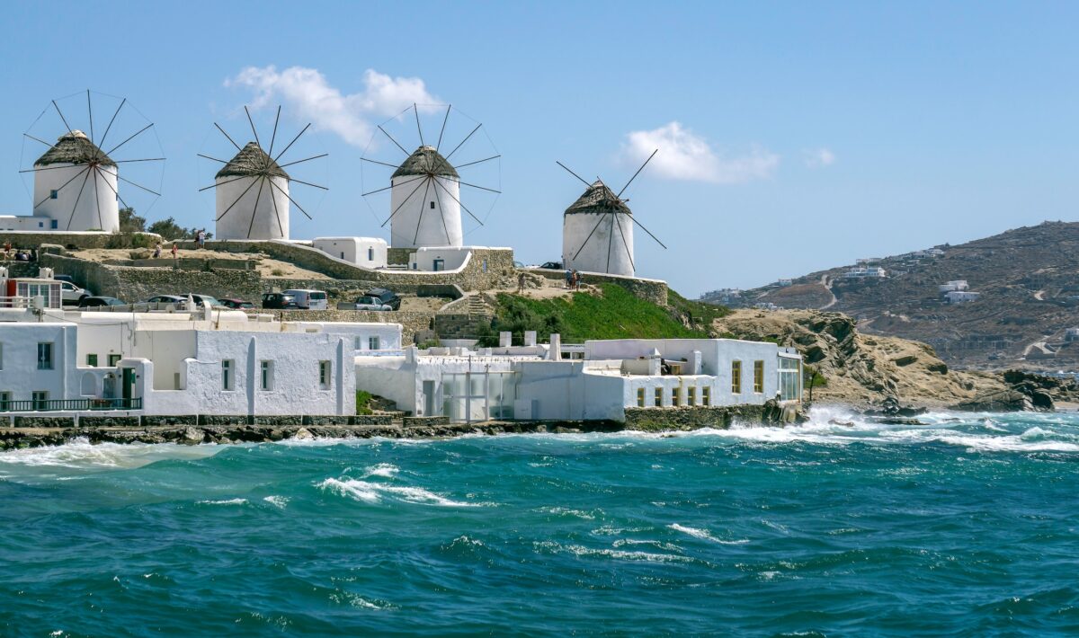 four white windmills overlooking the turquoise sea on the Greek island of Mykonos.