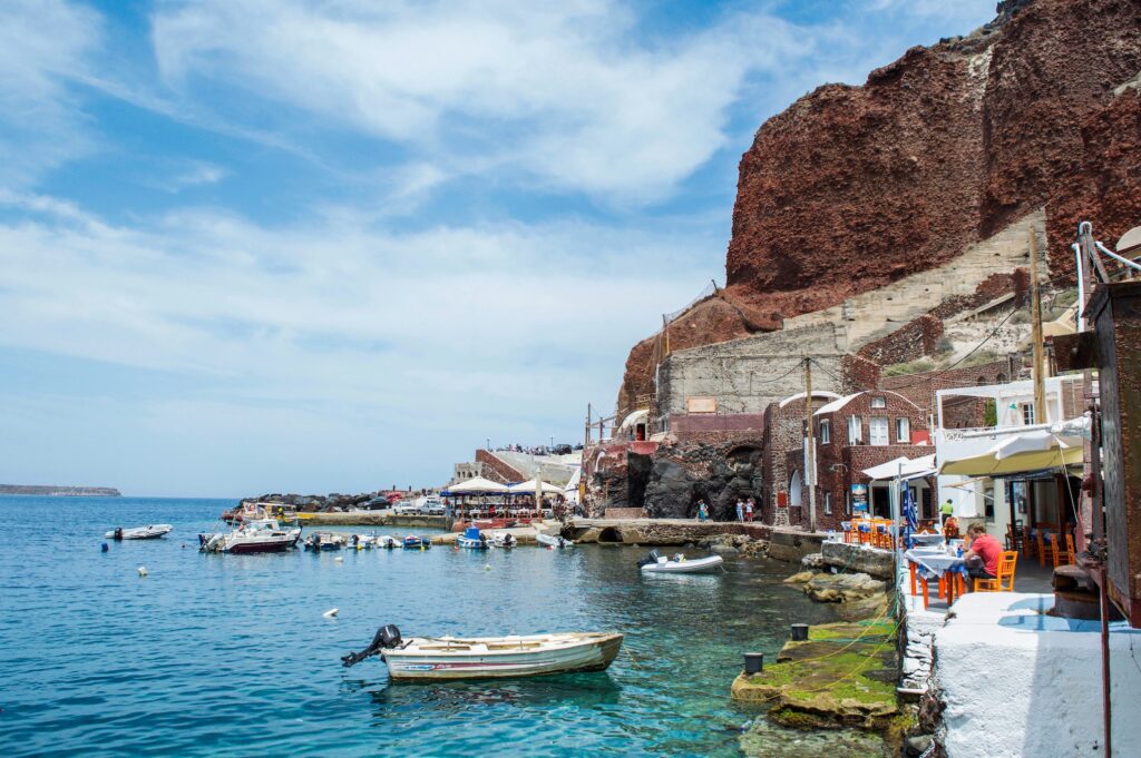 Santorini holidays can involve seeing seaside villages built on red volcanic cliffs near crystal blue waters.